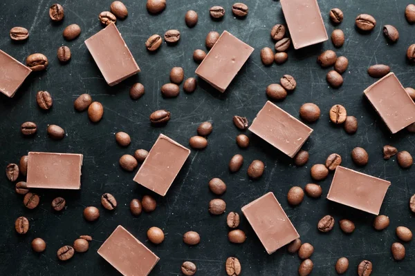 Granos de café con trozos de chocolate sobre fondo negro vista plana — Foto de Stock