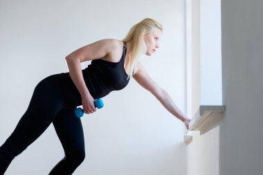 spor salonunda Dumbbell ile egzersiz yaparak sarışın kız