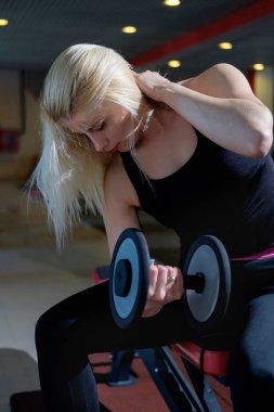 spor salonunda Dumbbell ile egzersiz yaparak sarışın kız