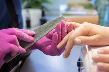 Manikürcü nailfile kullanarak tırnak parlatma