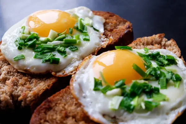 Two fried eggs on bread filling spring green onion close up — Stock Photo, Image