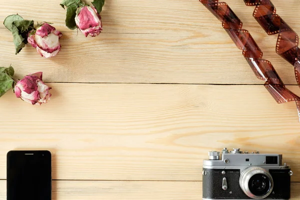Vista superior da mesa de madeira com smartphone, câmera vintage, filme a — Fotografia de Stock