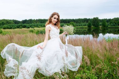 Gelinin portre beyaz düğün elbise ile buket yakın göl