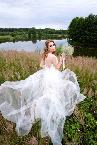 Portret van de bruid in witte bruiloft jurk met boeket in de buurt van lake, — Stockfoto