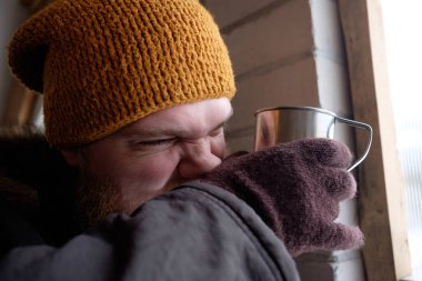 Kızıl saçlı sakallı sıcak kahve tutan kutup ceketli adamı veya