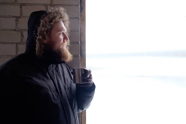 Redhead skäggig man i polar jacka håller kopp hett kaffe eller — Stockfoto