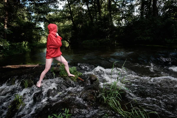 girl in red waterproof jacket fording mountain river