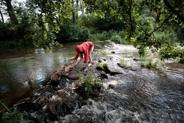 girl in red waterproof jacket fording mountain river