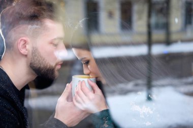 Genç çift sittiing yakın pencere ve t fincan holding