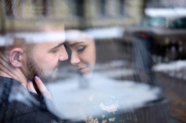 Genç çift sittiing pencere yakınındaki ve birbirlerine sarılmak