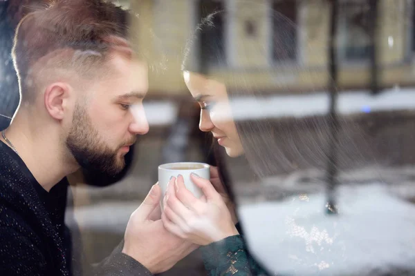 Unga kaukasiska par sittiing nära fönster och innehav kopp t — Stockfoto