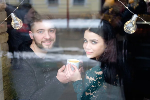 Joven pareja caucásica sentado cerca de ventana y sosteniendo taza de t — Foto de Stock