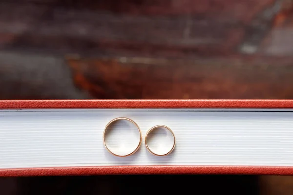 Brown wedding album with two wedding rings stay on brown wooden