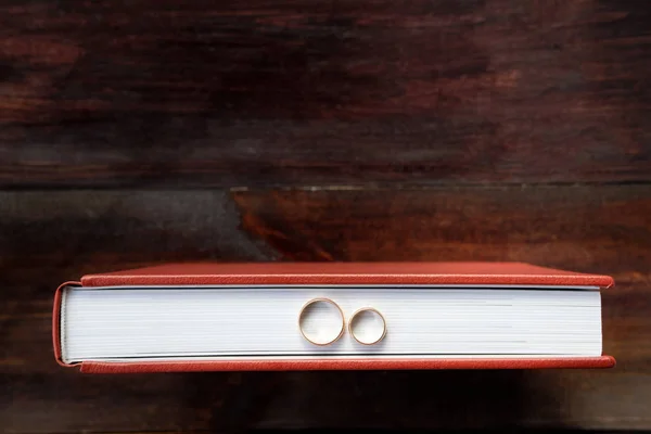 Brown wedding album with two wedding rings stay on brown wooden