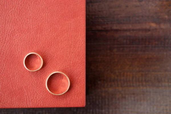 Brown wedding album with two wedding rings on surface lie on bro
