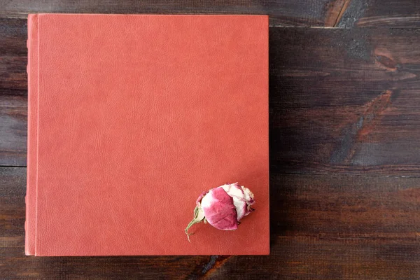 Brown wedding album with rose flower on surface lie on brown woo