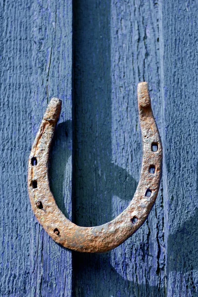 rusty iron horseshoe nailed down to wooden wall