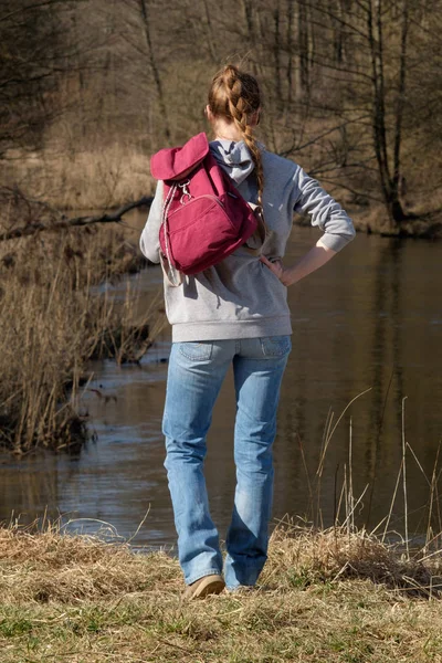Concepto de viaje. Chica de pie en la orilla del río vestida en je — Foto de Stock
