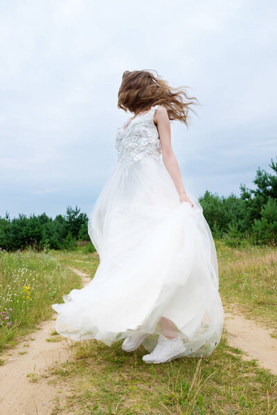 Young pretty bride in white wedding dress spin around