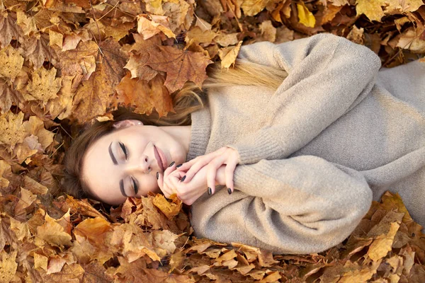 Glücklich lächelnde süße Mädchen mit geschlossenen Augen liegen im Herbst le — Stockfoto