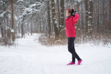 Pembe spor kıyafetli bir kadın at kuyruğu takıyor..