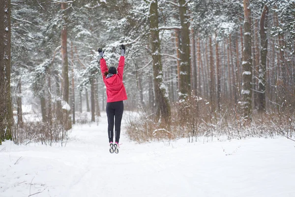 Χειμερινό τρέξιμο. Γυμνάζομαι. Νεαρή αθλητική γυναίκα άλμα στο δάσος το χειμώνα — Φωτογραφία Αρχείου