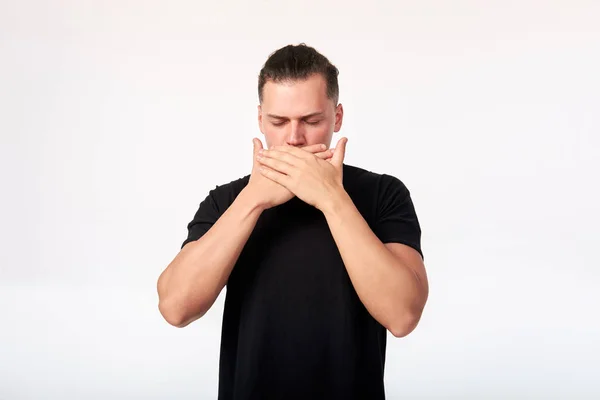 Emotions and feelings. Portrait of scared man with closed eyes covering his mouth with hands. Studio shot on white background.