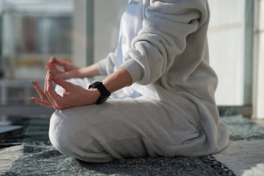 Beyaz kadın pijamalarıyla meditasyon yapıyor. Lotus pozisyonunda oturuyor.