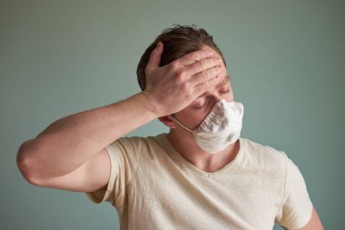 Tıbbi maskeli kötü görünümlü beyaz adam ateşten muzdarip.