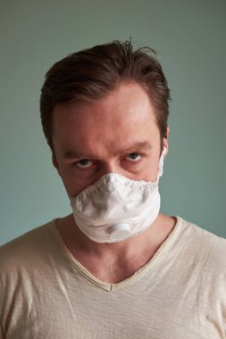 Koruyucu tıbbi maske takan beyaz adam kötü görünüyor.