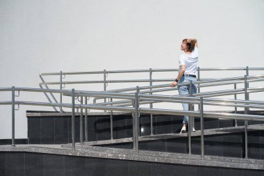 Kısa saçlı, beyaz saçlı genç kadın şehir merkezinde güneşlenmekten hoşlanıyor, yürüyüş yapıyor.