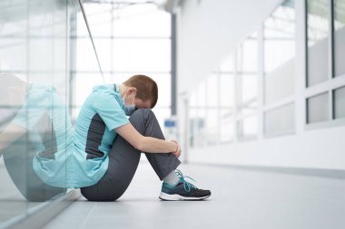 Tükenmiş konsept. Tükenmiş Kafkas kadın kısa saç kesimi doktoru kliniğin koridorunda gözleri kapalı oturuyor ve üzgün görünüyor.