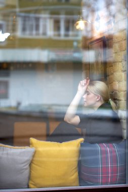 Kafenin penceresinin yanında oturan tatlı, şehvetli, sarışın kadın. Dinlenme zamanı..                                