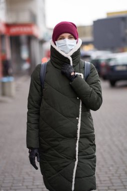 Salgın sırasında şehir dışında tıbbi maske takan beyaz bir kadın. 