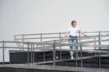 Kısa saçlı, beyaz saçlı genç kadın şehir merkezinde güneşlenmekten hoşlanıyor, gözlerini kapalı tutuyor.