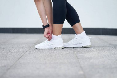 Siyah spor taytlı, şık beyaz spor ayakkabılı kadın bacakları. Eğitimde olan zayıf bir kadın. Başlamaya hazır.                              