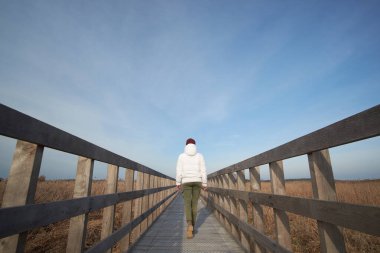 Kız, Narew Milli Parkı 'nın bataklığında yürüyor, arkadan bakıyor.