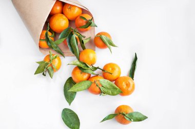 Kağıt% 100 geri dönüşümlü ve yeniden kullanılabilir. Turuncu taze mandalina ya da yeşil yapraklı mandalina beyaz arka planda yatar. Üst görünüm.