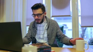 Genç adam dizüstü bilgisayar ve içecek kahve çalışma