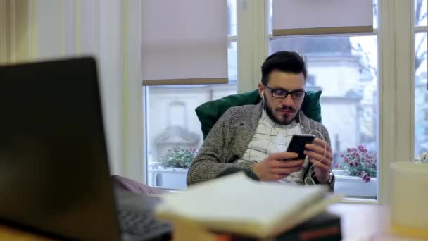Молодой человек слушает музыку на своем рабочем месте — стоковое видео