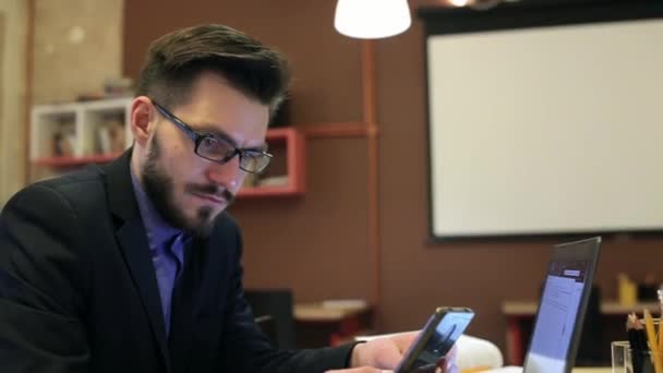 Een jonge man met laptop op zijn werkplek — Stockvideo