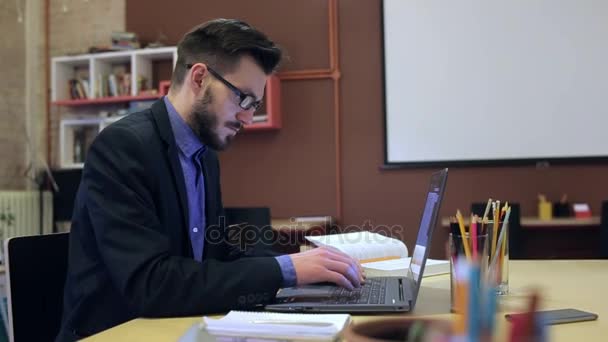 A young man using laptop on his workplace — Stock Video
