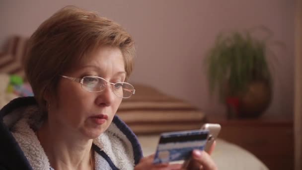 Mujer con regalos en el fondo utilizando el teléfono inteligente para ir de compras en línea con tarjeta de crédito . — Vídeos de Stock