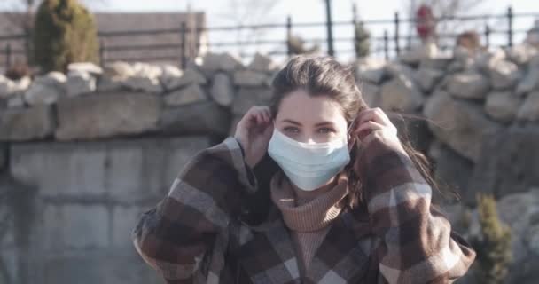 Portret van een jonge student vrouw met een beschermend masker op straat. — Stockvideo