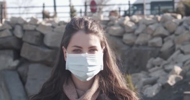 Portret van een jonge student vrouw met een beschermend masker op straat. — Stockvideo