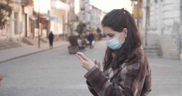 Jonge vrouw in beschermend masker met behulp van een mobiele telefoon. — Stockvideo