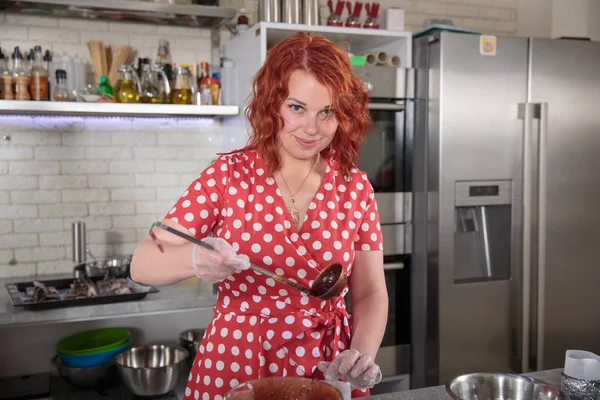 Rothaarige Frau in der Küche mit einer Kelle — Stockfoto