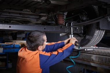 Mechanic Works on a Car in body shop clipart