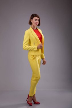 Glamour moda stil katalog rahat kıyafetler tarihi toplantı iş kadını için parti seksi güzel kadın esmer çekim saç giymek sarı kostüm mükemmel vücut şekli modeli takım elbise yürümek