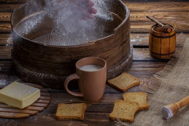 Eller un elek sprey. tereyağı, kraker, bir fincan bal süt ahşap arka plan üzerinde